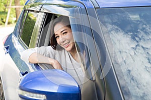 Young Asian woman driving a car and smile happily with glad positive expression during the drive to travel journey.