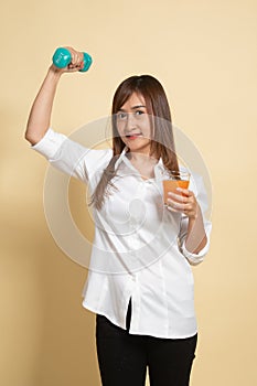 Young Asian woman with dumbbell drink orange juice