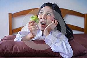 Young Asian woman eating green apple on bed in morning.