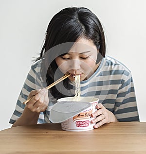 A young asian woman eating an instant noodles
