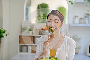 Young Asian woman eating salad vegetable in diet concept