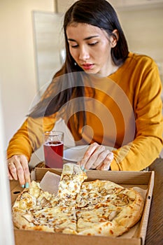 Young Asian woman eats a pizza ordered from an app. Food delivery