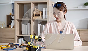 Young Asian woman engineer programer working on robotics project at home.