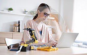 Young Asian woman engineer programer working on robotics project at home.
