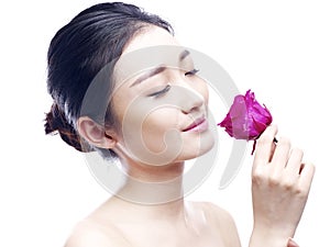 Young asian woman enjoying fragrance of red rose