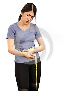 Young asian woman in exercise clothes use a tape measure to measure around the waist. Looked at the number on the tape measure