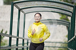 Young asian woman exercising outdoor in yellow neon jacket, jogging