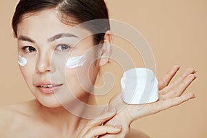 Young asian woman with facial cream jar