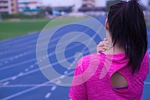 Young asian woman feel pain on her neck and shoulder while running or jogging on running track. Health care and medical concept