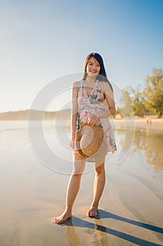 Young Asian woman feeling happy on beach, beautiful female happy relax smiling fun on beach near sea when sunset in evening.