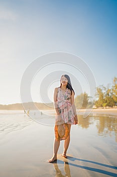Young Asian woman feeling happy on beach, beautiful female happy relax smiling fun on beach near sea when sunset in evening.