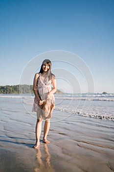 Young Asian woman feeling happy on beach, beautiful female happy relax smiling fun on beach near sea when sunset in evening.