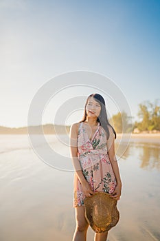 Young Asian woman feeling happy on beach, beautiful female happy relax smiling fun on beach near sea when sunset in evening.