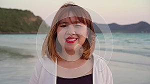 Young Asian woman feeling happy on beach, beautiful female happy relax smiling fun on beach near sea when sunset in evening.