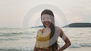 Young Asian woman feeling happy on beach, beautiful female happy relax smiling fun on beach near sea when sunset in evening.