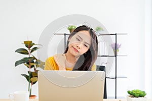 Young asian woman feeling pain in neck and shoulder after working on computer laptop for a long time
