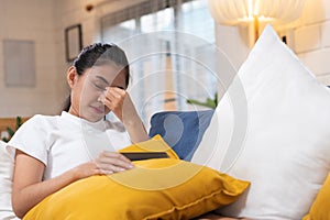 Young asian woman feeling  stress  and closed eyes  suffering from headache and lying down on sofa in living room,tired  female of photo