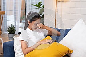 Young asian woman feeling  stress  and closed eyes ,she is  suffering from headachelying down on sofa in living room,tired  female