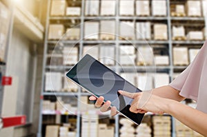 Young Asian woman finger pointing to tablet doing stocktaking of product in cardboard box on shelves in warehouse,