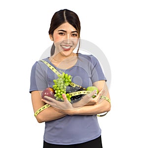 Young asian woman in fitness clothes holding fruits with measuring tape. Portrait on white background with studio light. Healthy