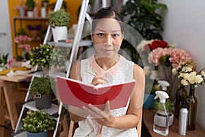 Young asian woman florist smiling confident writing on notebook at flower shop