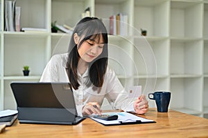 Young Asian woman hand calculating expenses and debt from credit card. E-commerce, financial planning and expenses