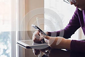 Young asian woman hand holding mobile smart phone and use stylus pen write on digital computer tablet