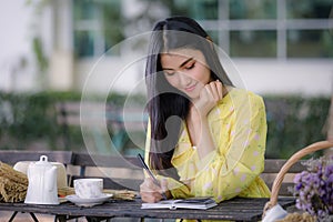 Young asian woman hand is writing on notepad with a pen in the garden