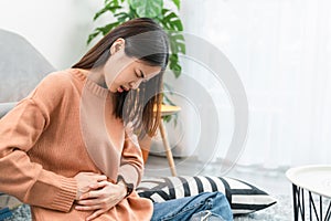 Young Asian woman hands holding the stomach and pain period cramps because having menstruation.