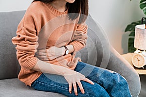 Young Asian woman hands holding the stomach and pain period cramps because having menstruation.