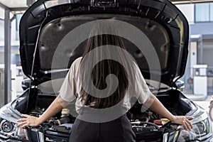 A young Asian woman has a broken car in the middle of the way and must call a mechanic to fix it. Portrait of young woman standing