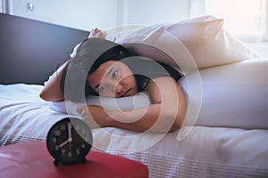 Young asian woman hates getting stressed waking up early,Female stretching her hand to ringing alarm to turn off alarm clock