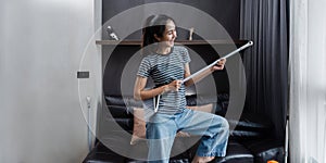 young asian woman having fun during cleaning, fooling with mop and broom