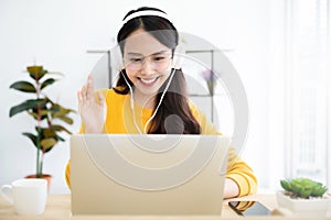 Young asian woman in headphone having conversation chatting while using laptop at house