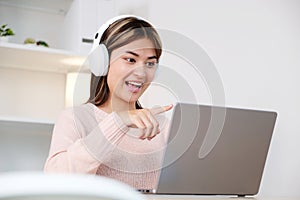 Young asian woman with headphones while make video conference by laptop computer