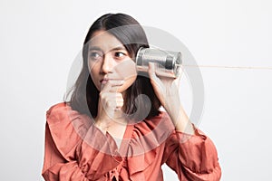 Young Asian woman hearing with tin can phone and thinking