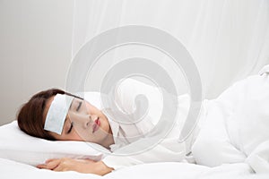 Young Asian woman with high fever while sleeping on white bed at home.