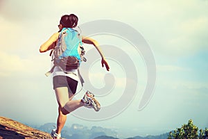 Young asian woman hiker running on mountain peak