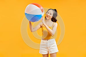 Young asian woman holding beach ball isolated on vivid background