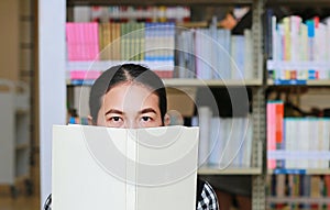 Young asian woman holding book on face in the library