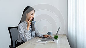 Young asian woman holding credit card and looking on laptop for online shopping