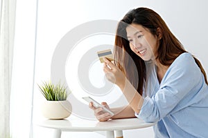 Young asian woman holding credit card and using smart phone for