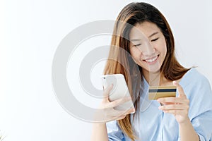 Young asian woman holding credit card and using smart phone for