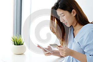 Young asian woman holding credit card and using smart phone for