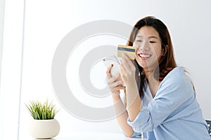 Young asian woman holding credit card and using smart phone for