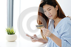 Young asian woman holding credit card and using smart phone for