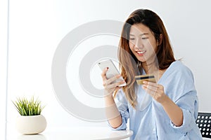 Young asian woman holding credit card and using smart phone for