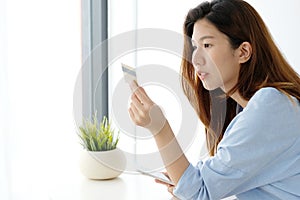 Young asian woman holding credit card and using smart phone for
