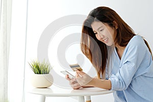 Young asian woman holding credit card and using smart phone for