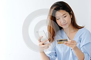 Young asian woman holding credit card and using smart phone for